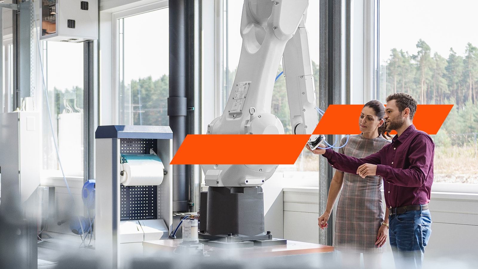 Man and woman looking at a robot arm