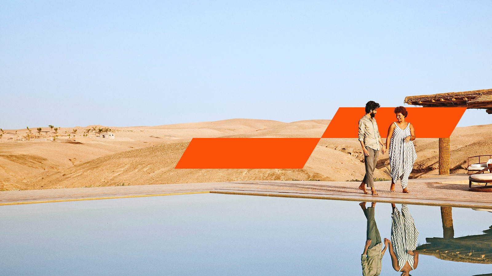 Man and woman walking by a pool in a desert