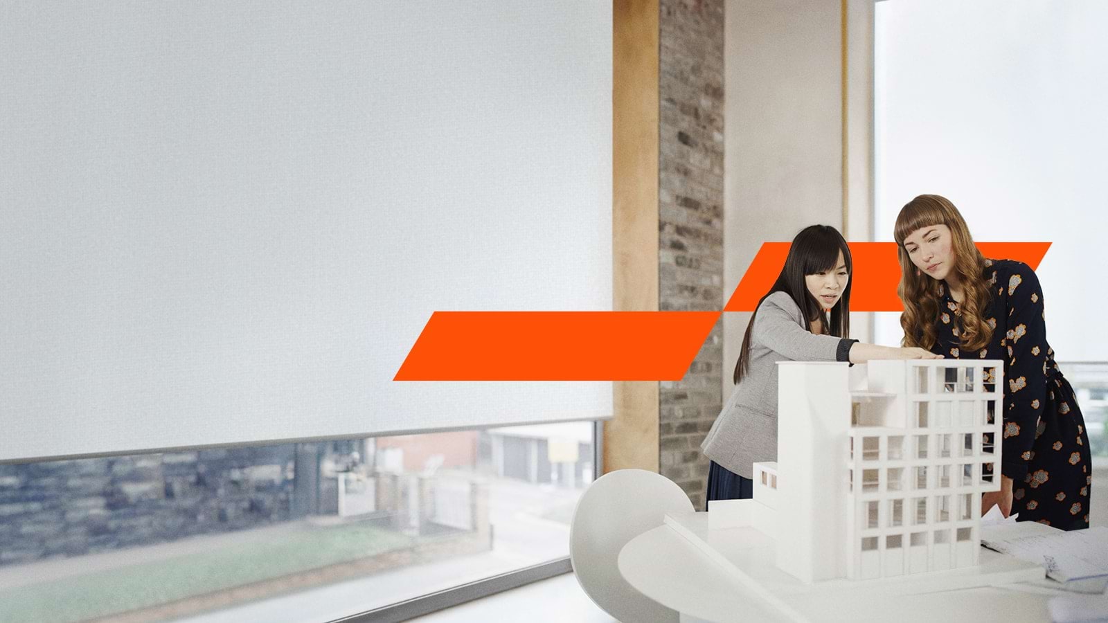 Two women looking at a house made of paper
